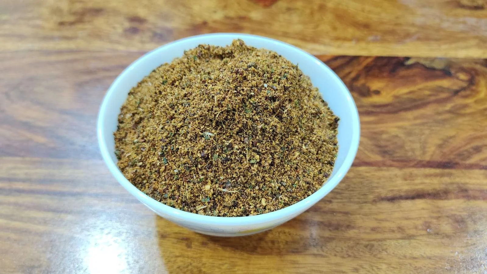 A bowl of homemade nalla karampodi, a flavorful South Indian chutney powder made with roasted lentils, spices, and red chilies for a bold taste.